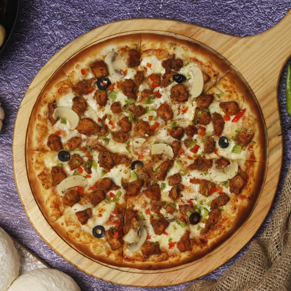 Positano's Pizza with chicken, mushrooms, olives, and bell peppers on a wooden board.